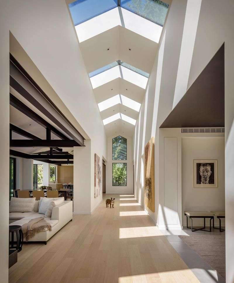 This modern home is organized around a central gallery spine with skylights that draw…