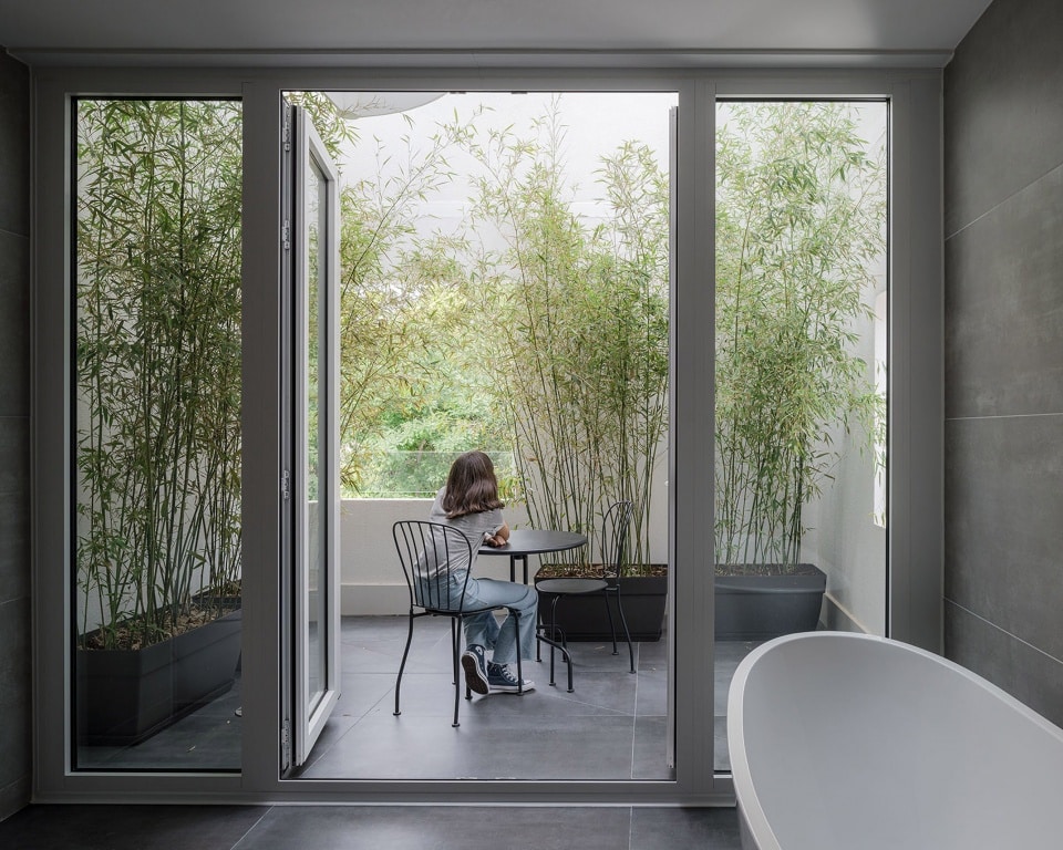 "Person sitting in an integrated indoor garden within a narrow house design."