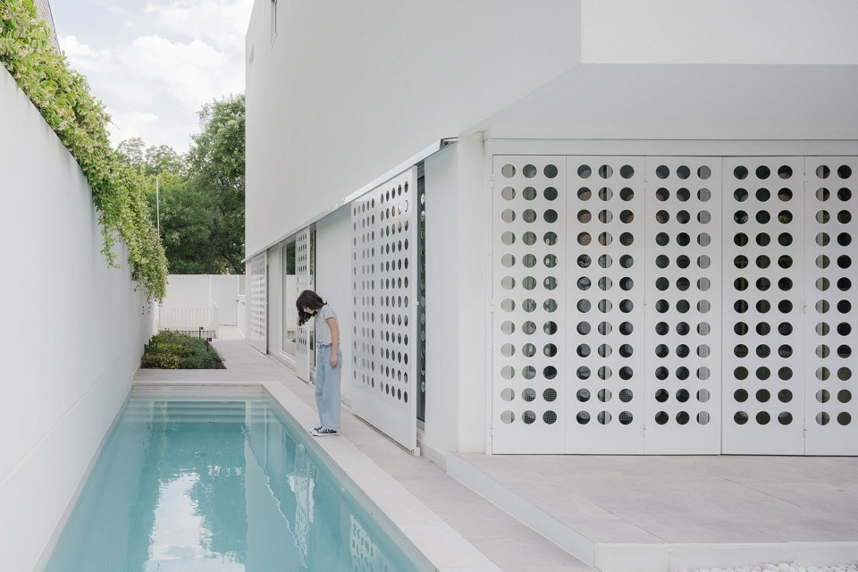 "Person standing near a bathtub surrounded by a pool in a narrow house design."