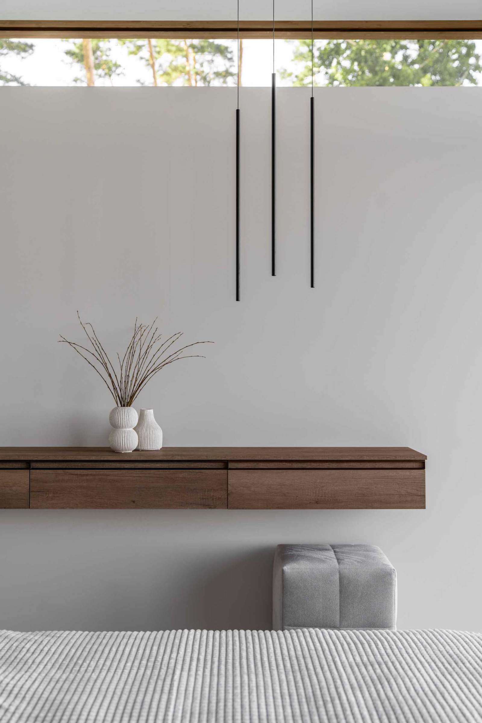 A modern bedroom with a floating wood shelf with drawers.