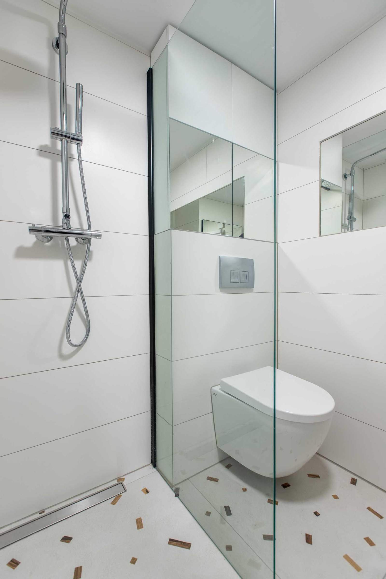 White walls keep this small bathroom bright, while flecks on the floor add a colorful element.