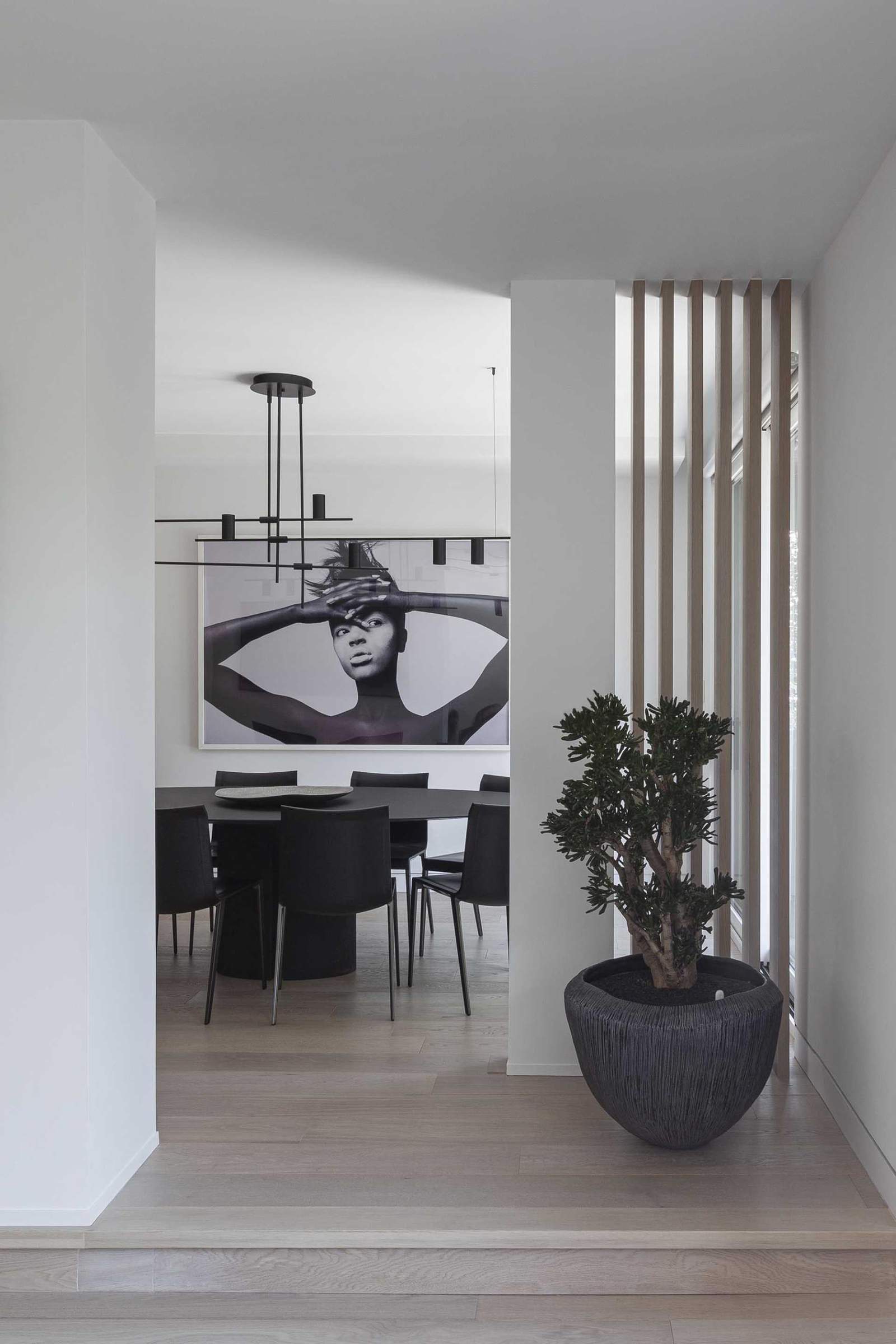 A modern dining area with a round black table, and a minimalist light fixture.