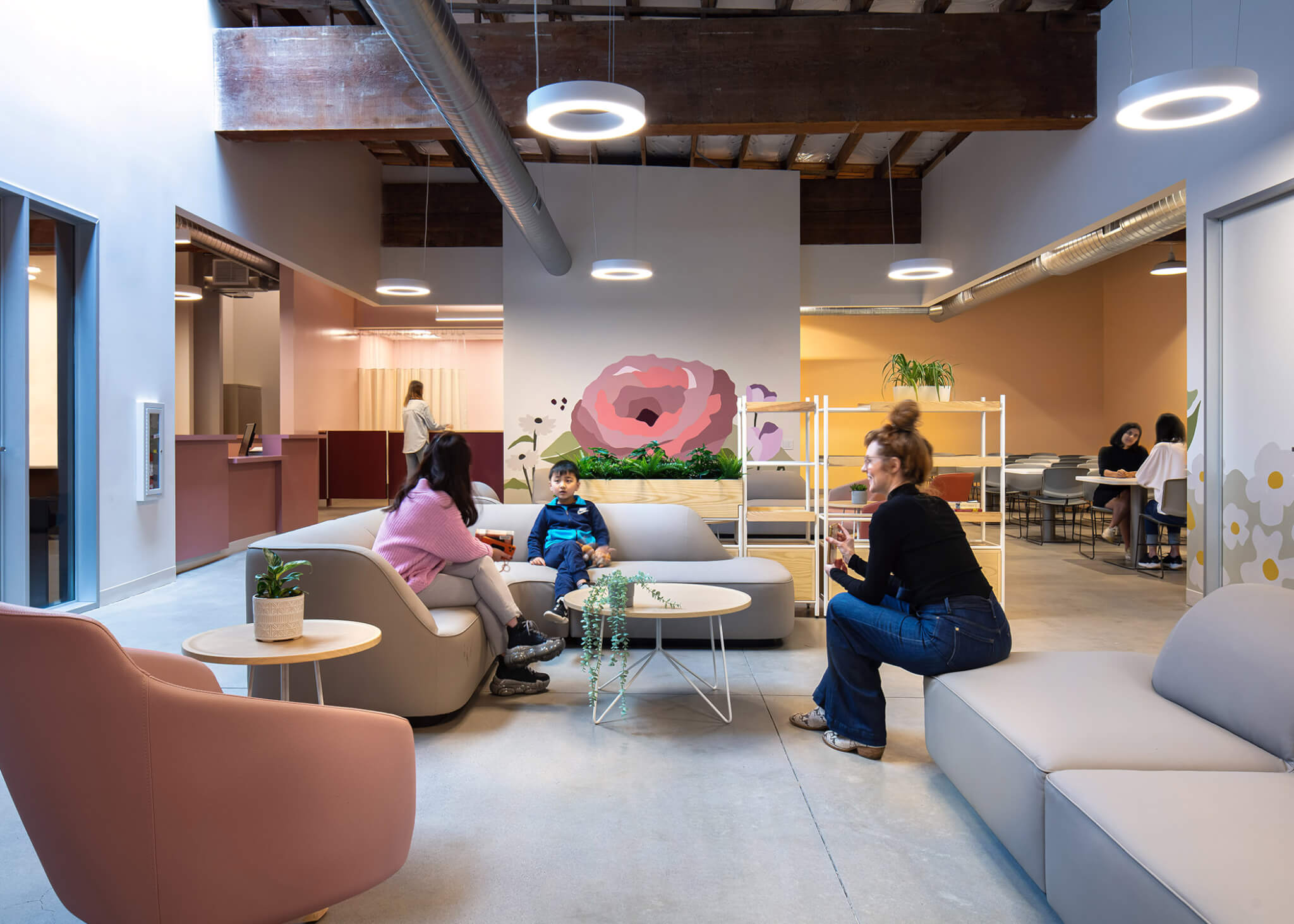 people converse in a large room with comfortable furniture and exposed wood beams