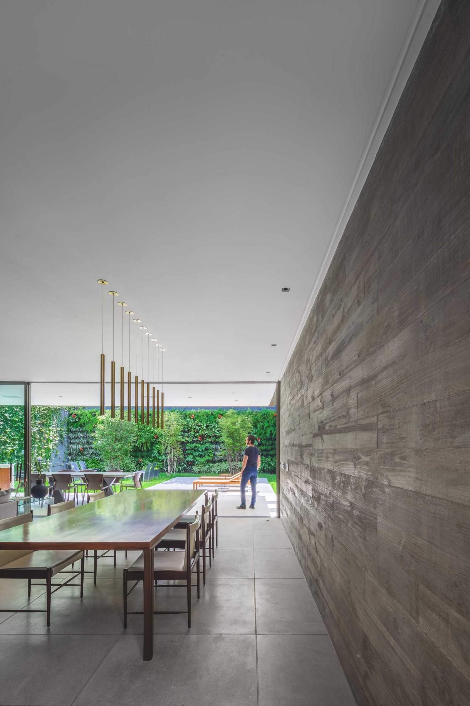 A concrete wall in this modern dining room, which has been left bare, and allows the minimalist pendant lights above the dining table to stand out.