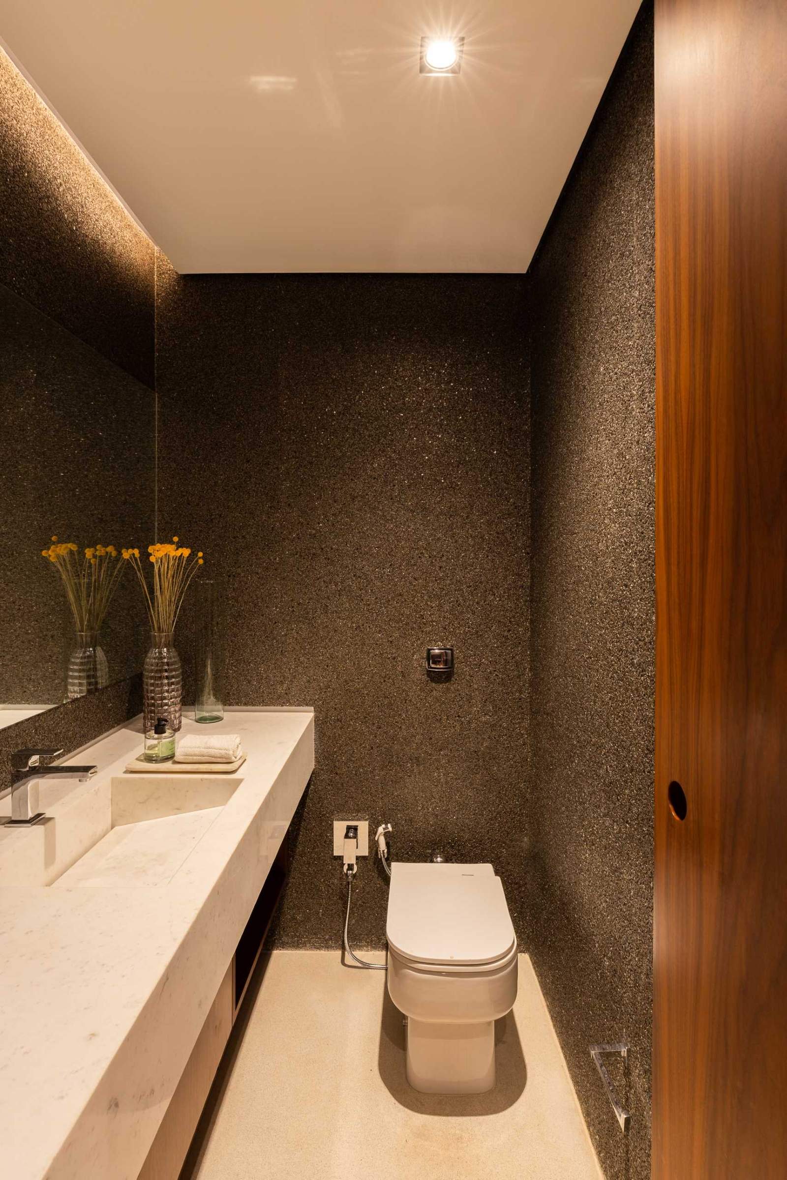 A powder room with dark walls and hidden lighting.