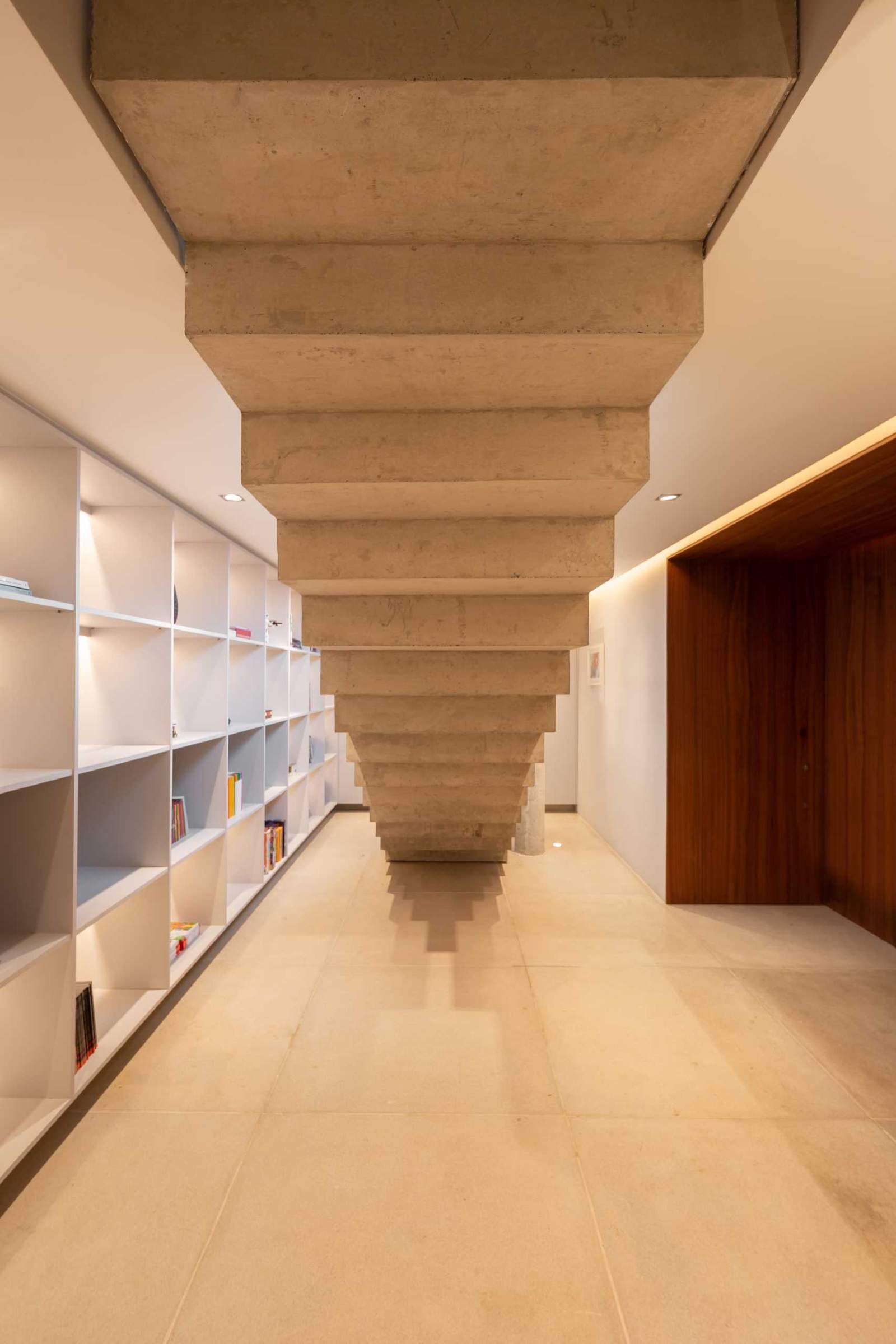 Concrete stairs lead down to a basement that has a wall of shelving with hidden lighting.