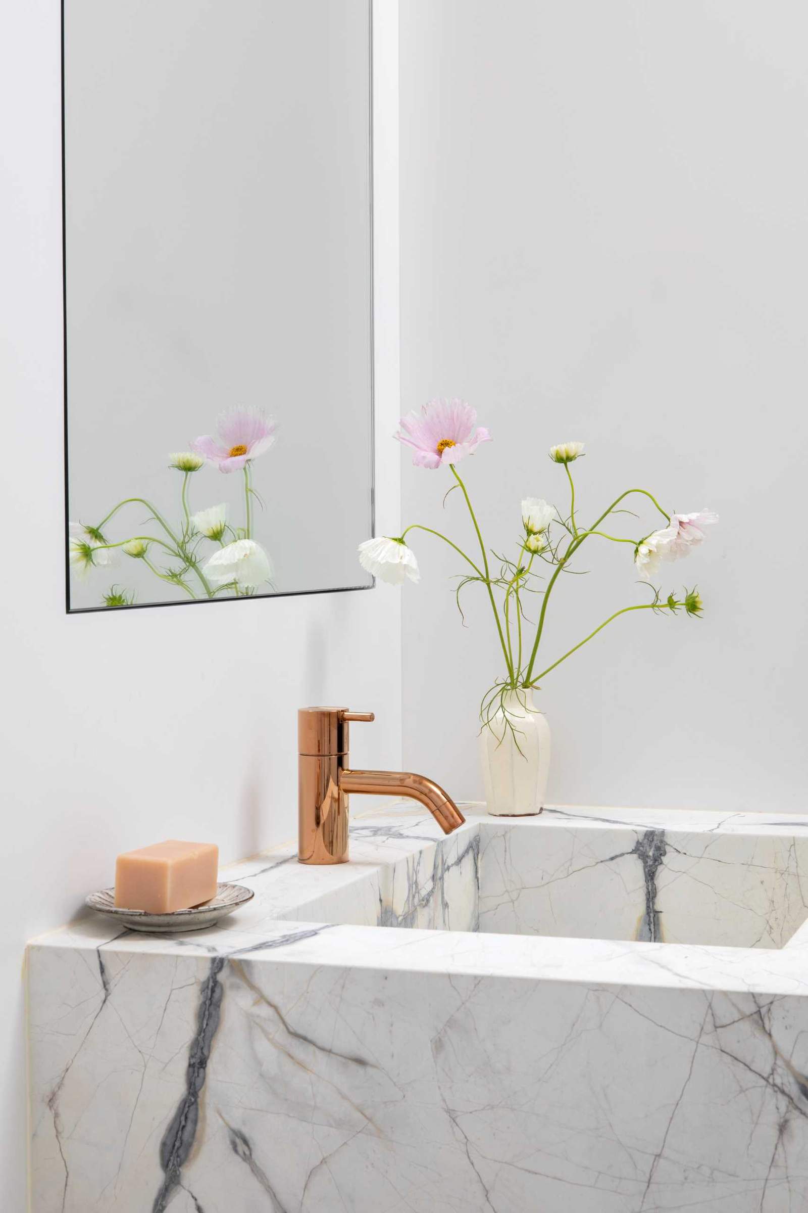 A modern bathroom that's enveloped in veined marble with accents of bright metallics.