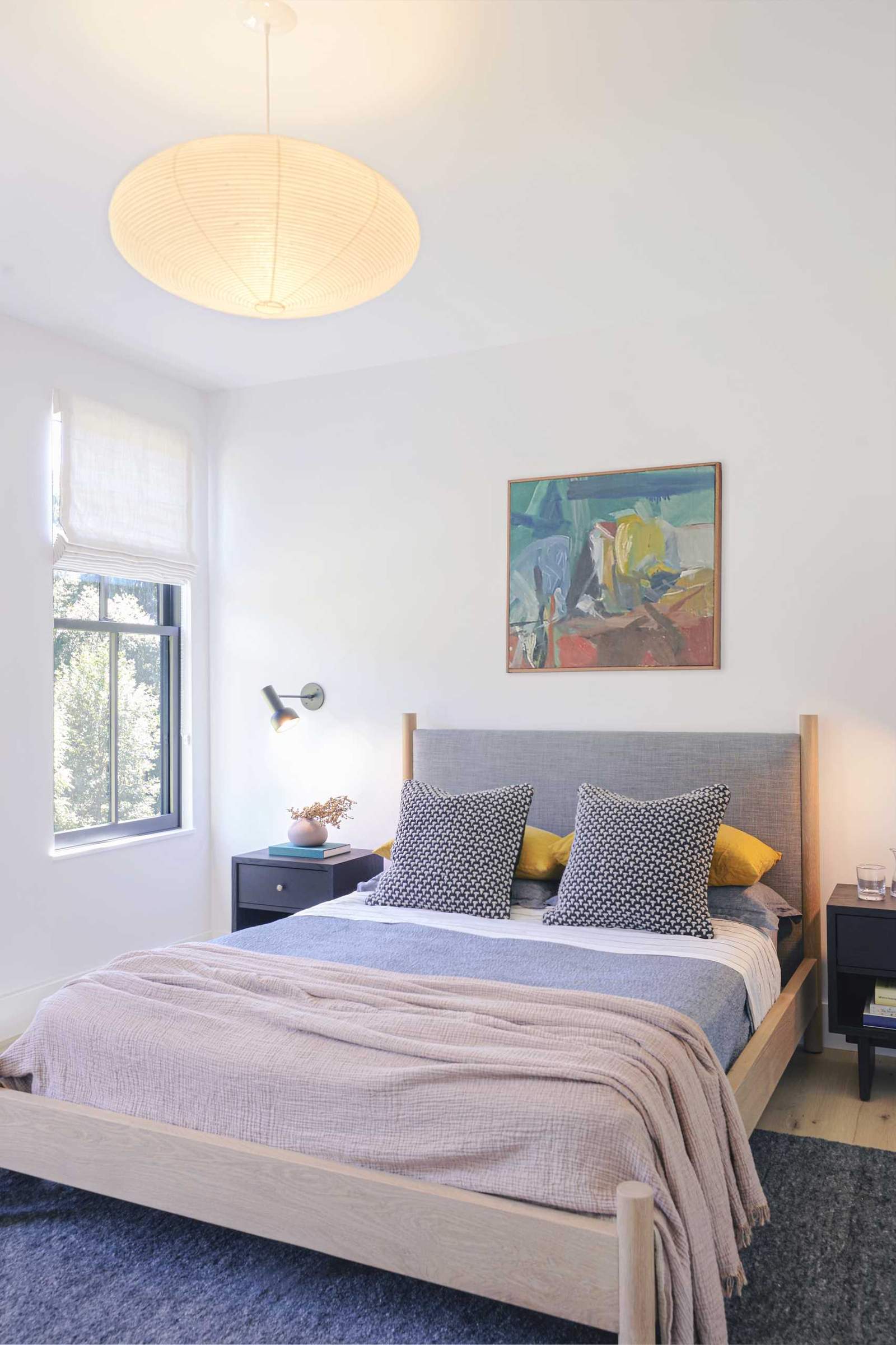غرفة نوم حديثة بجدران ذات ألوان فاتحة وإطار سرير خشبي.