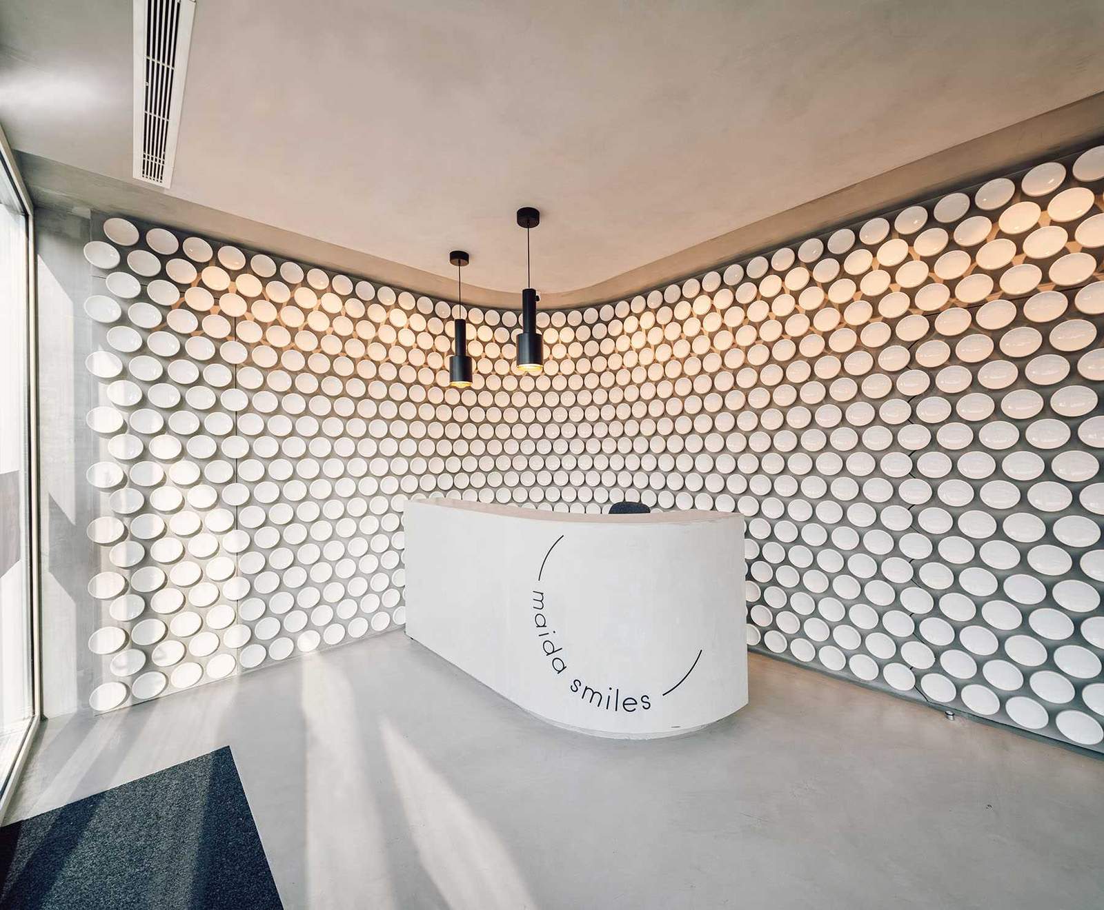 More than 500 hand-crafted ceramic discs line the wall of this modern dental clinic, while microcement covers the floor.