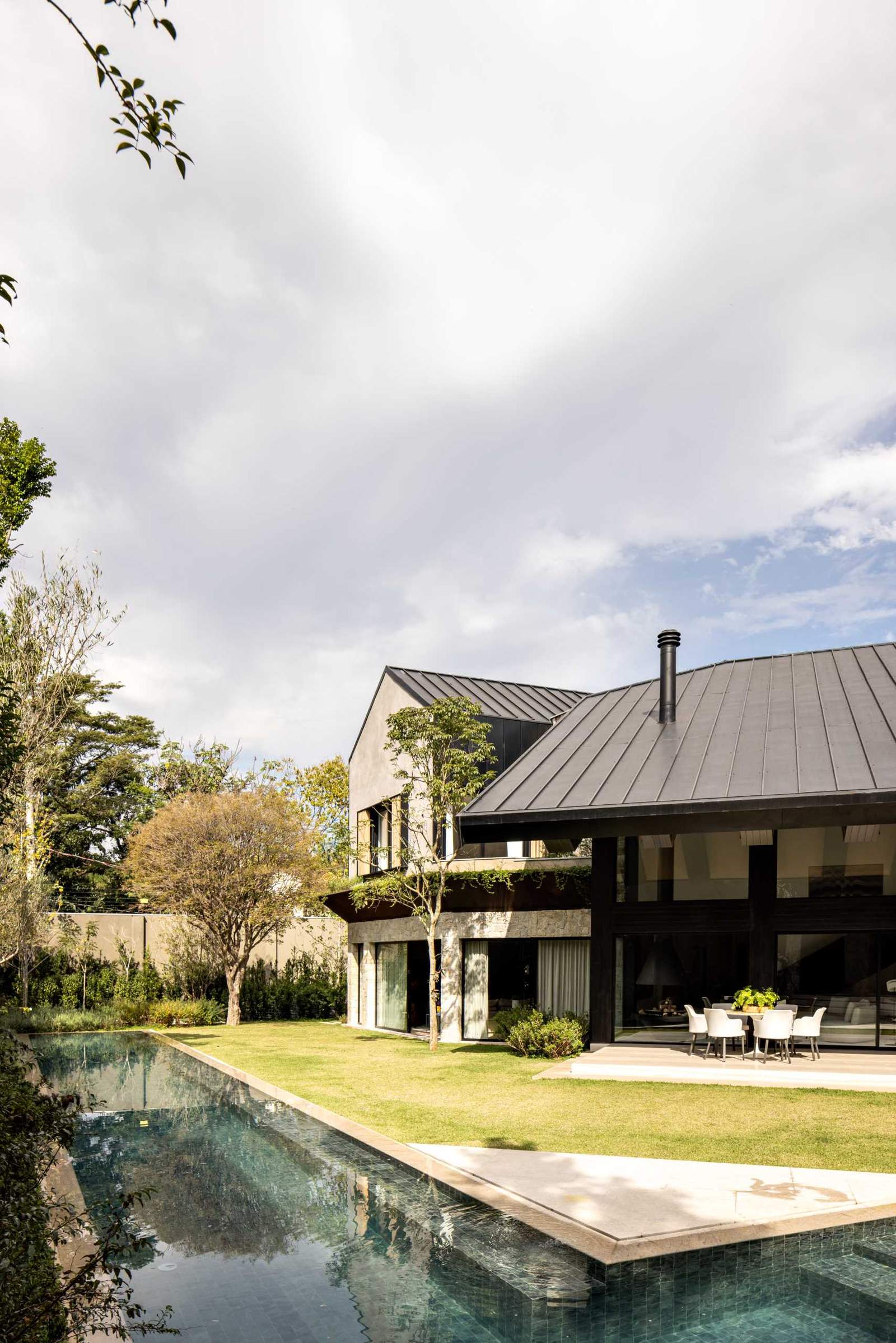 A modern home includes a planter that wraps around its exterior, separating the main and upper floors.