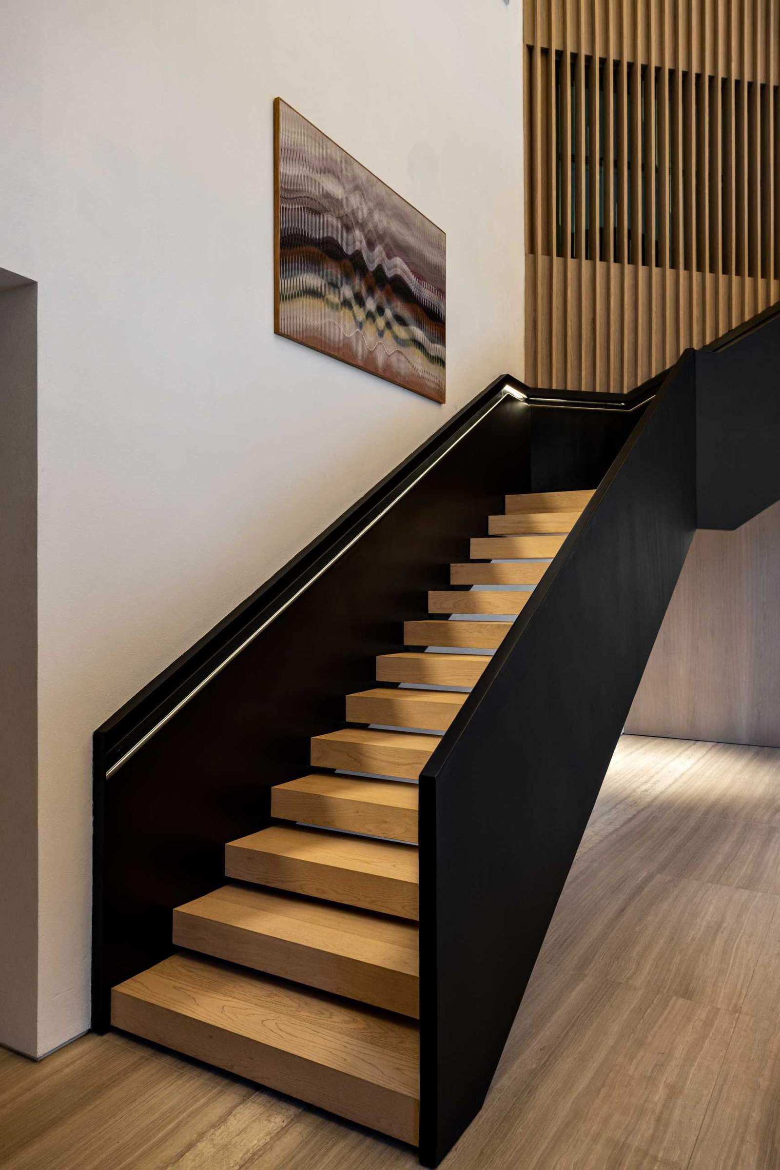 Black and wood stairs that lead to the upper floor of the home, where the bedrooms and bathrooms are located.