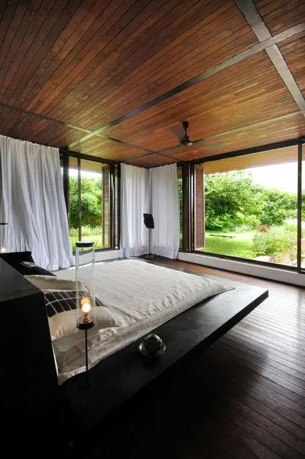 Modern bedroom with wide windows offering a view of the garden."