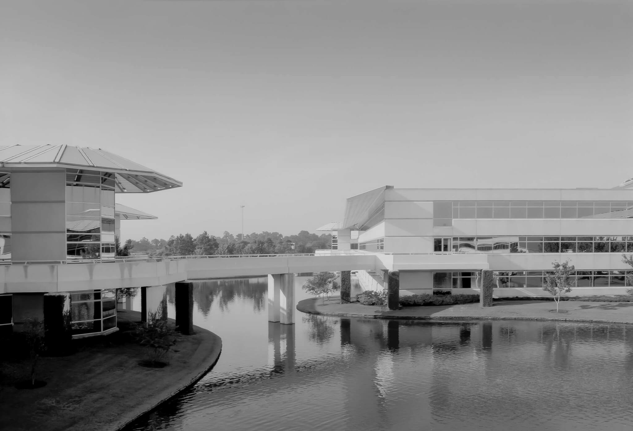 black and white photo of building spanning over waterway