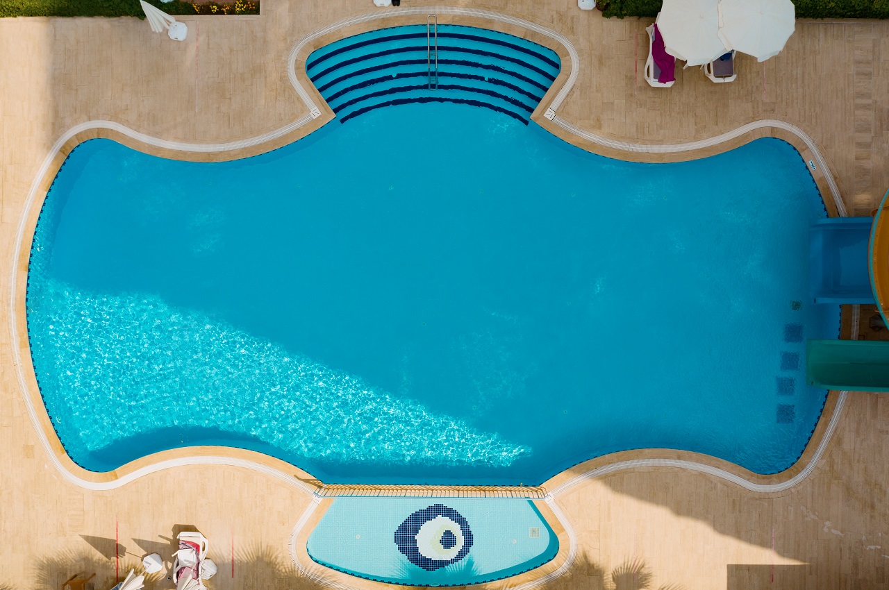 Aerial view of swimming pool outside hotel. Beautiful pool ready to holiday tourists. Irregularly-shaped swimming pool.