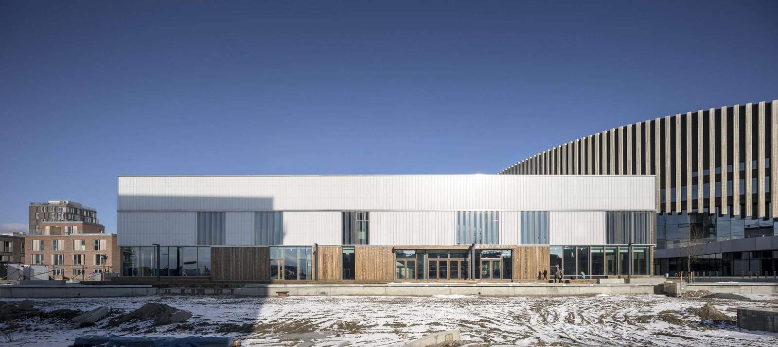 واجهة Ørestad Ice Rink مع عناصر زجاجية شفافة وشفافة ، جنبًا إلى جنب مع الألواح الخشبية.