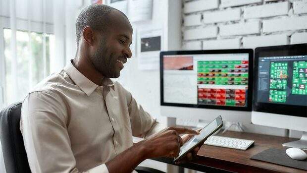 Man on a tablet in a office and a computer