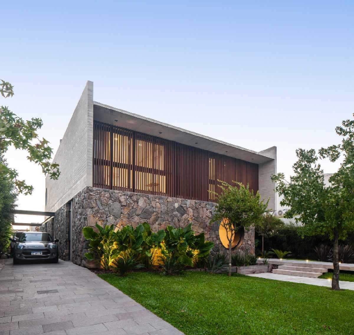 A Round Window Is Nestled Into A Stone Wall On The Front Of This Home