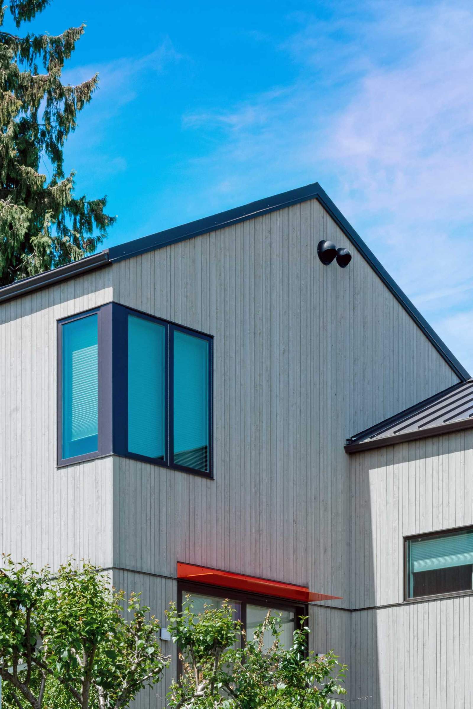 A modern house with wood siding and dark window frames.