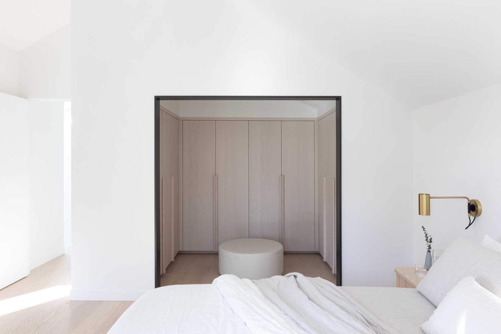 غرفة نوم حديثة بها خزانة ملابس مفتوحة مع خزائن خشبية فاتحة اللون.
