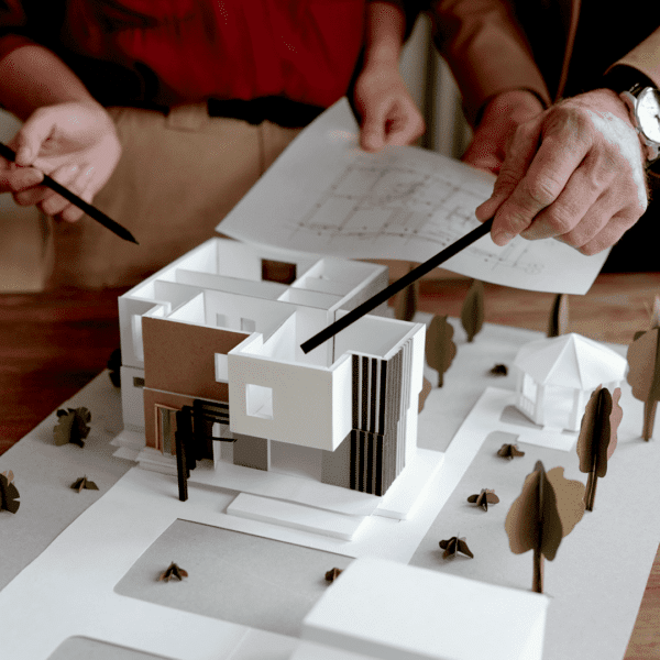 A team of engineers reviewing an architectural model for a sustainable building design with a focus on environmental sustainability.