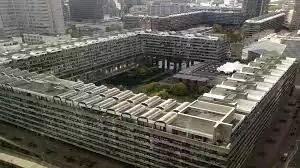 مجمع مباني يُظهر تصميمًا هندسيًا بسيطًا وملموسًا للعمارة البروتالية، باستخدام أسطح خرسانية خام وأبعاد هندسية واضحة.