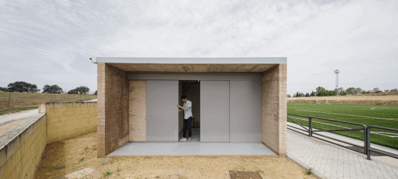 elongated brick-clad changing room completes small football field in seville