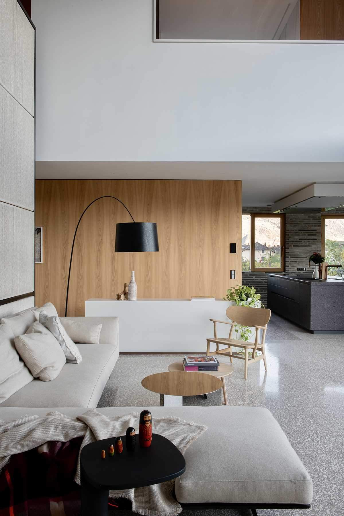 A modern living room is open to the nearby kitchen and dining area.