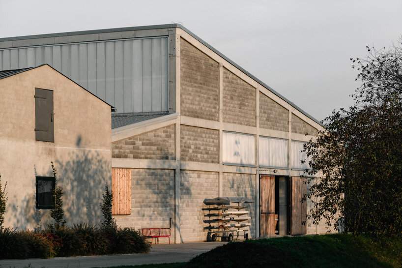 raw concrete, steel panels, and wood wrap wiercinski studio's equestrian center in poland
