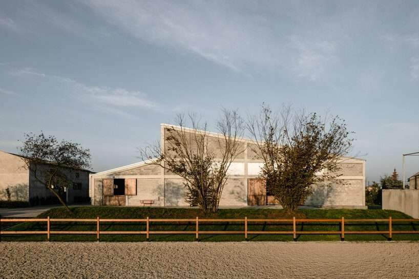 raw concrete, steel panels, and wood wrap wiercinski studio’s equestrian center in poland