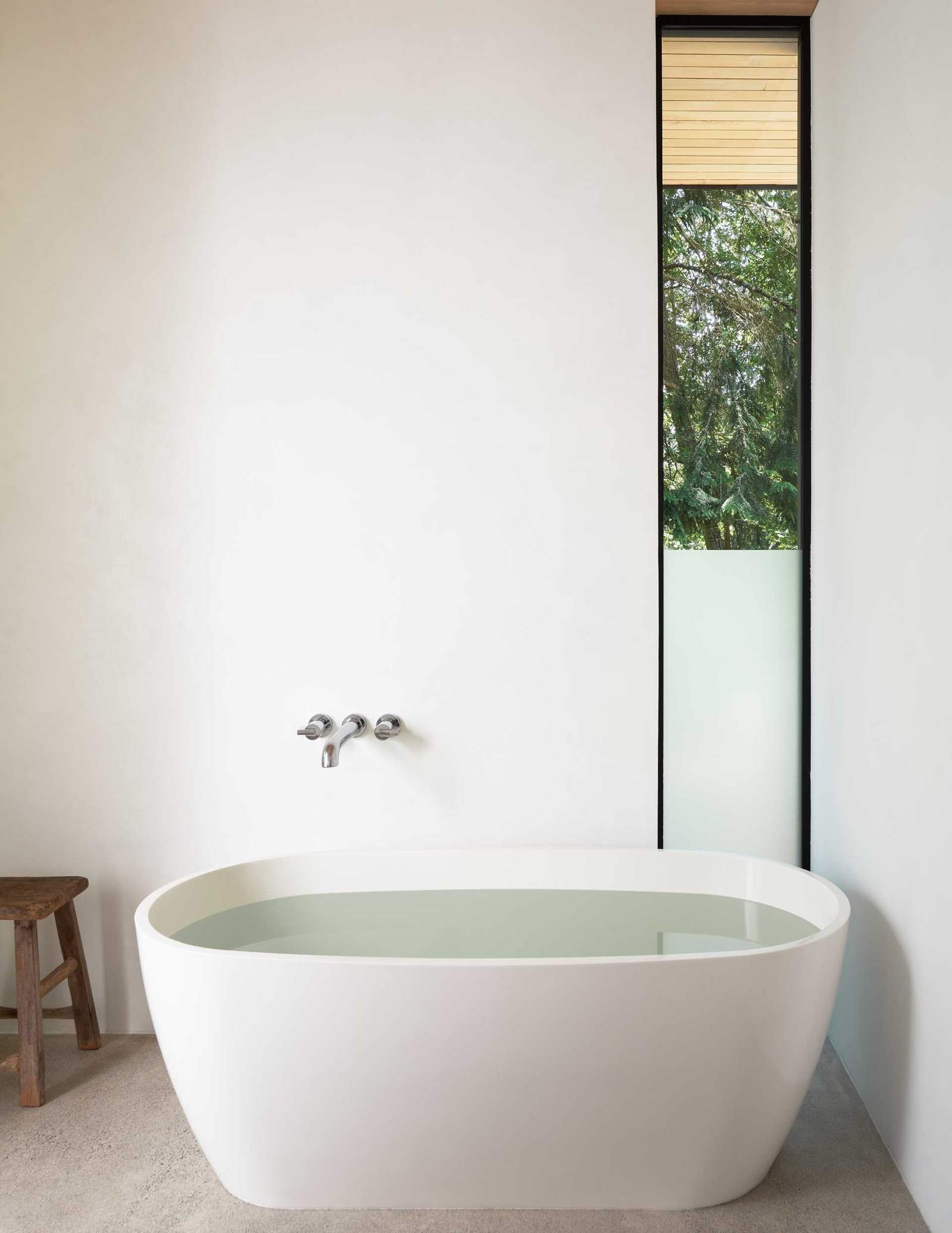 A modern bathroom with a freestanding bathtub and vertical window.