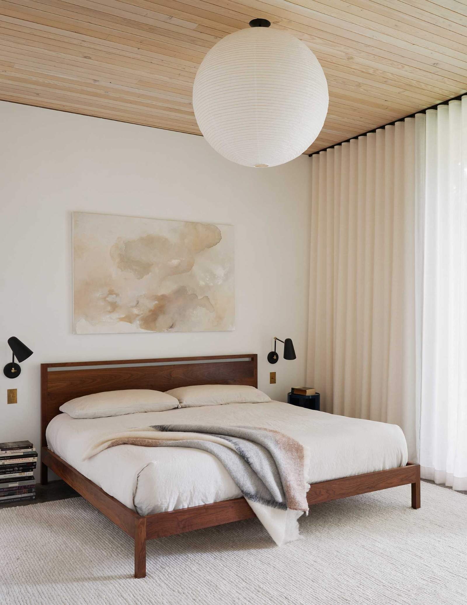 This modern bedroom features a custom bed designed by the architects and built by Joel Kikuchi, while an ivory woven wool rug softens the polished concrete floor.