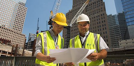 "Two architects reviewing engineering plans at a large construction site, highlighting the importance of collaboration in project execution."