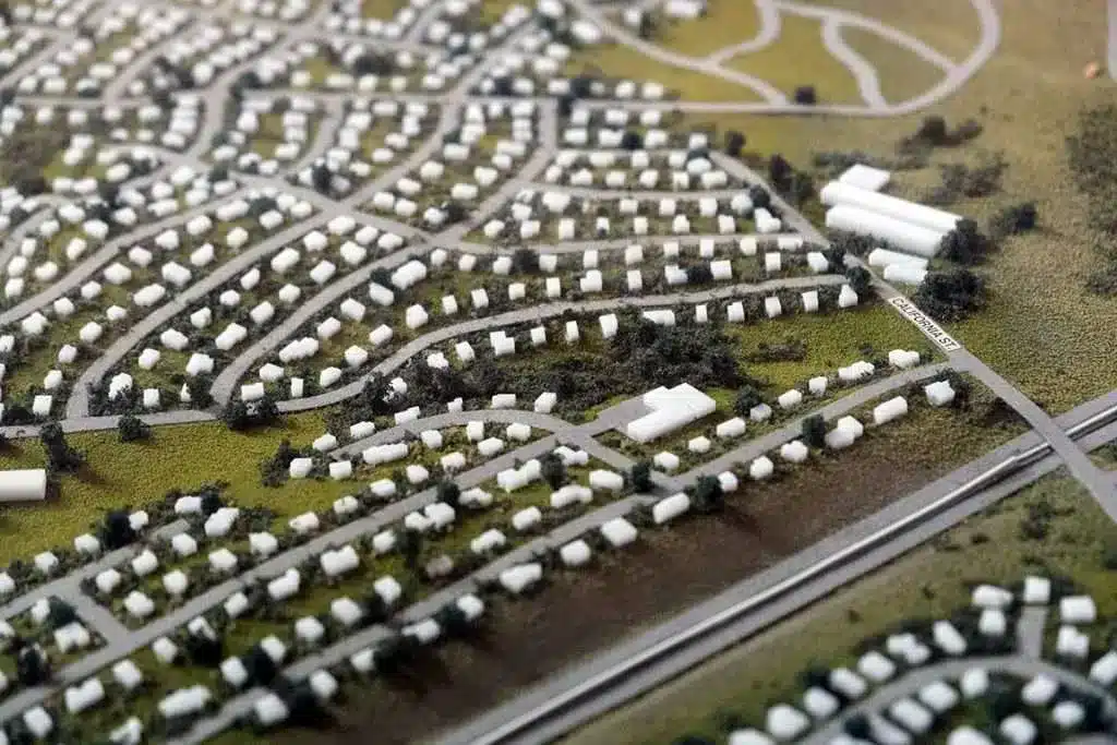 "A miniature model of an urban design showcasing detailed planning for roads, houses, and pathways, highlighting the role of architects in city planning."