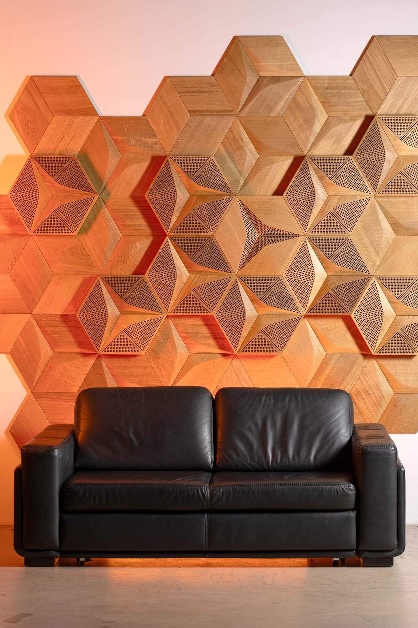 أريكة موضوعة أمام لوحات خشبية صوتية كبيرة من إنتاج شركة Form at Wood.
