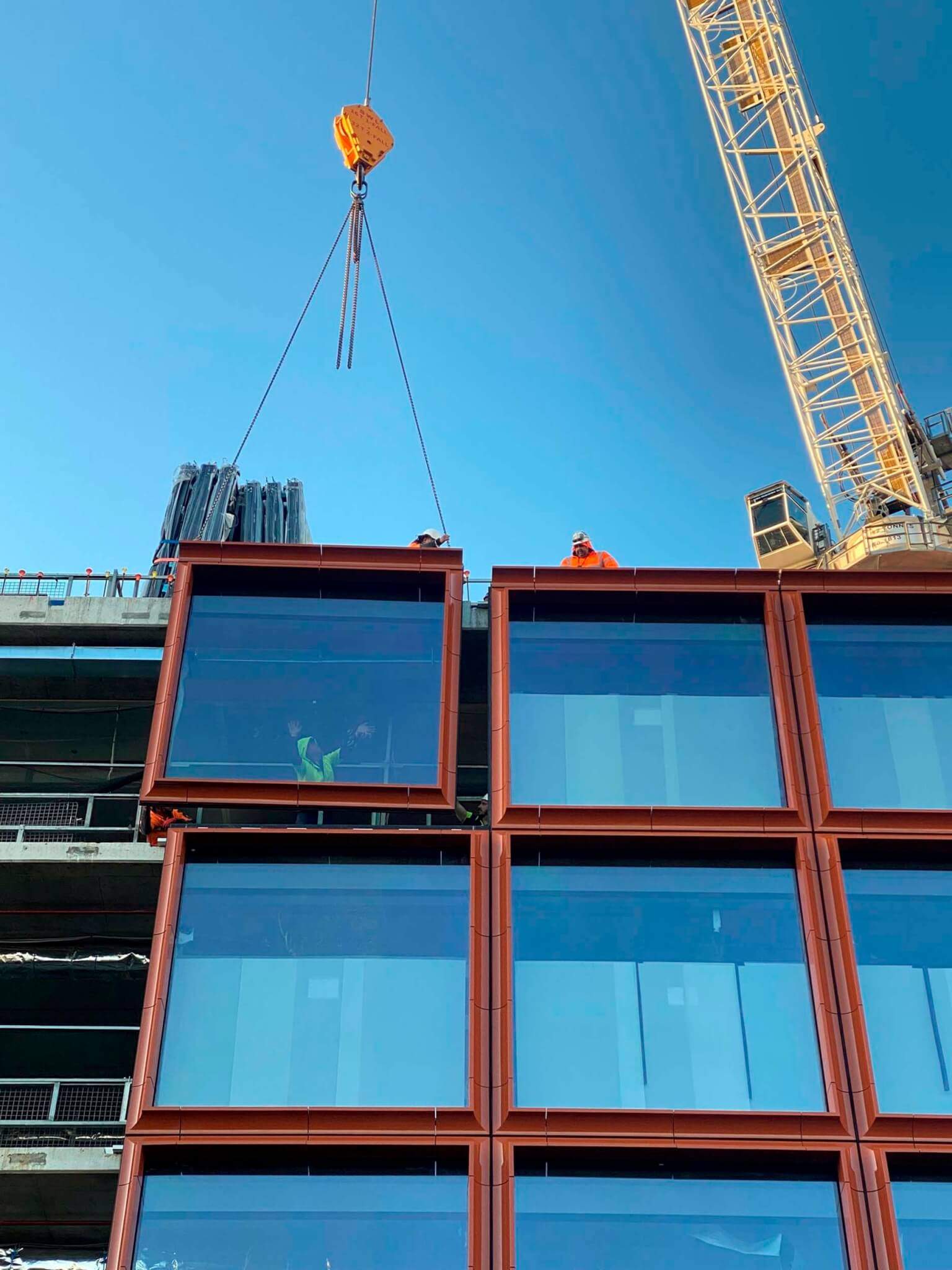 the building is framed with large glass panels and terra-cotta 