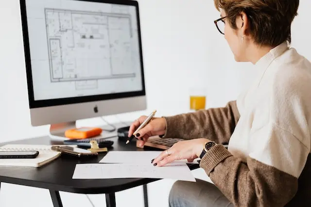 An architect using a computer to design digital building plans, highlighting the role of modern technology in architecture.