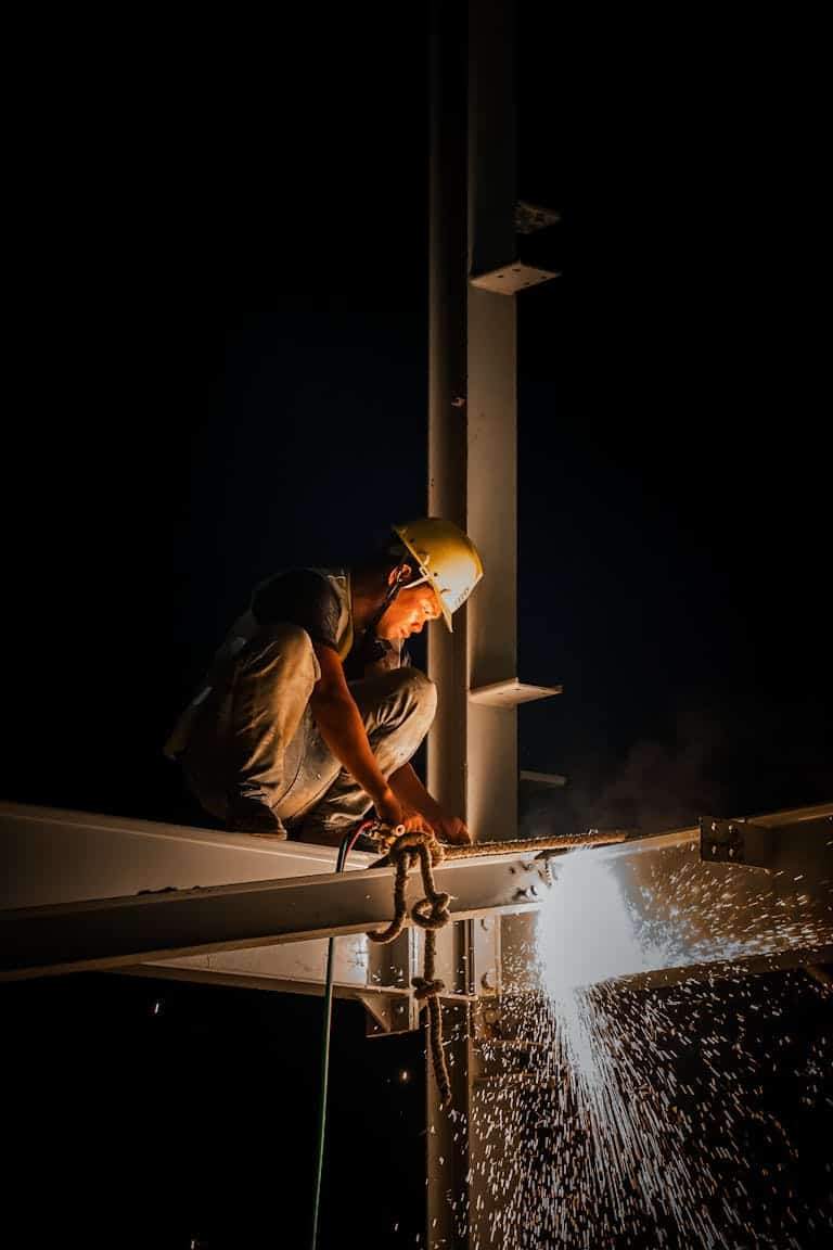 Worker Welding Steel Beams at Night