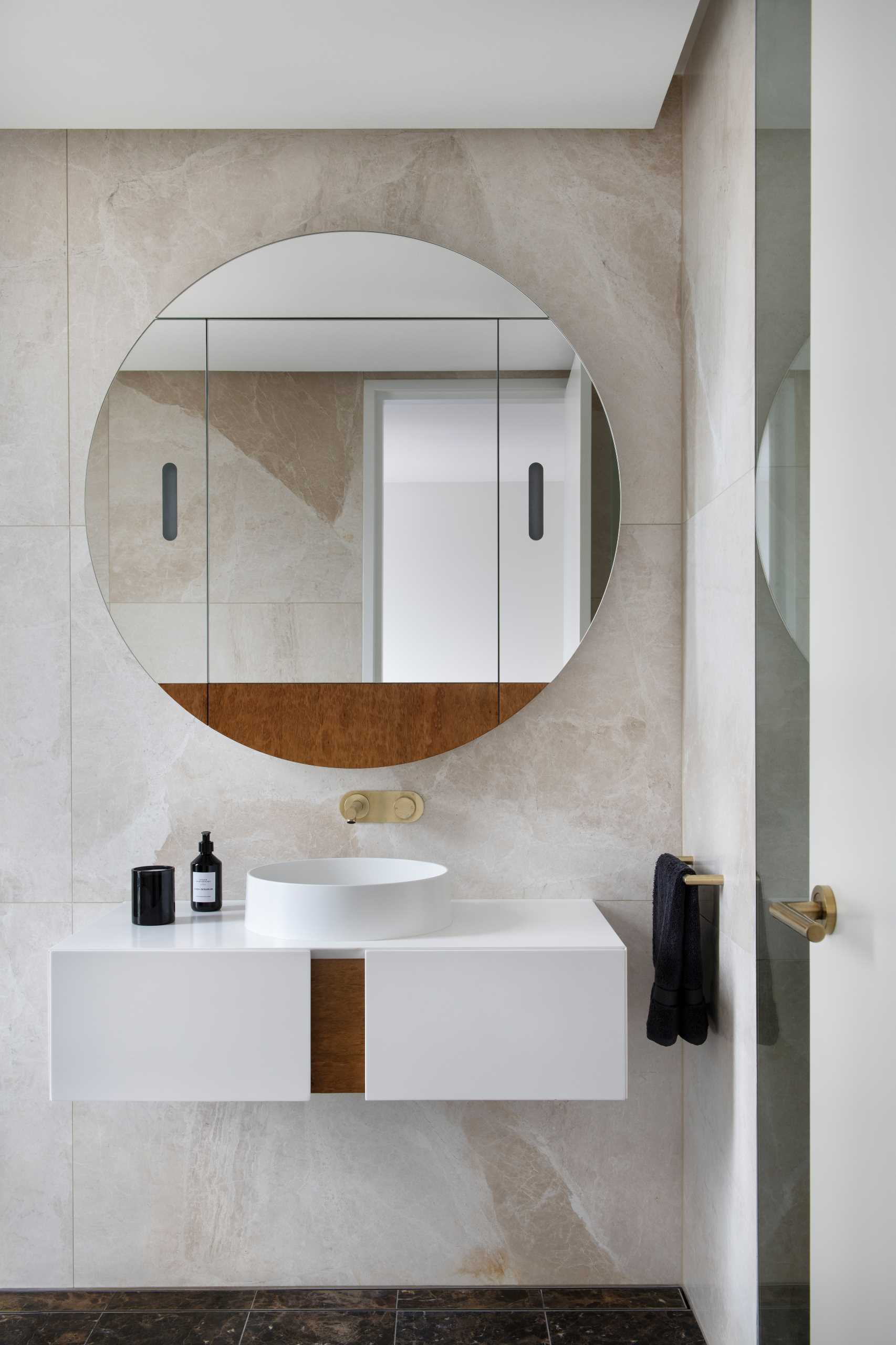 حمام معاصر به منضدة زينة عائمة ومرآة مستديرة.