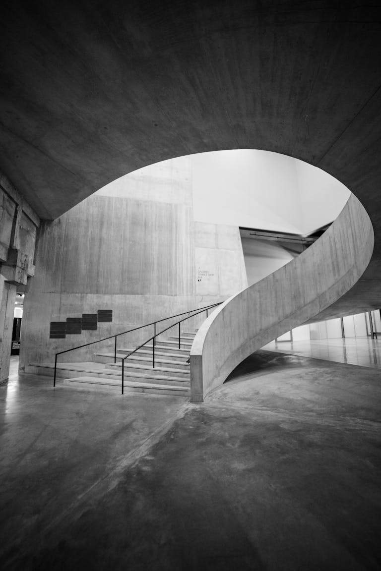 Black and white photo of a modern spiral staircase inside Tate Modern, London.