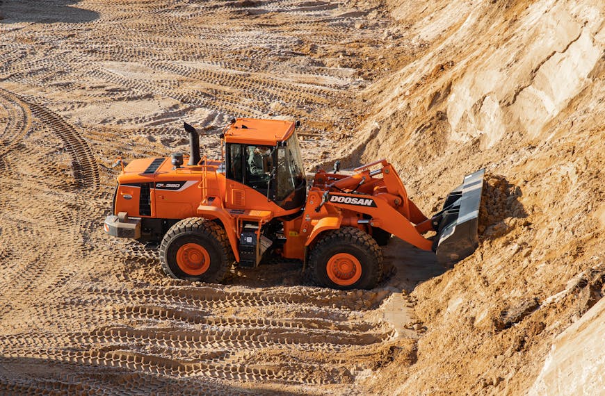 High-angle shot of an orange wheel loader working on a sandy construction site.