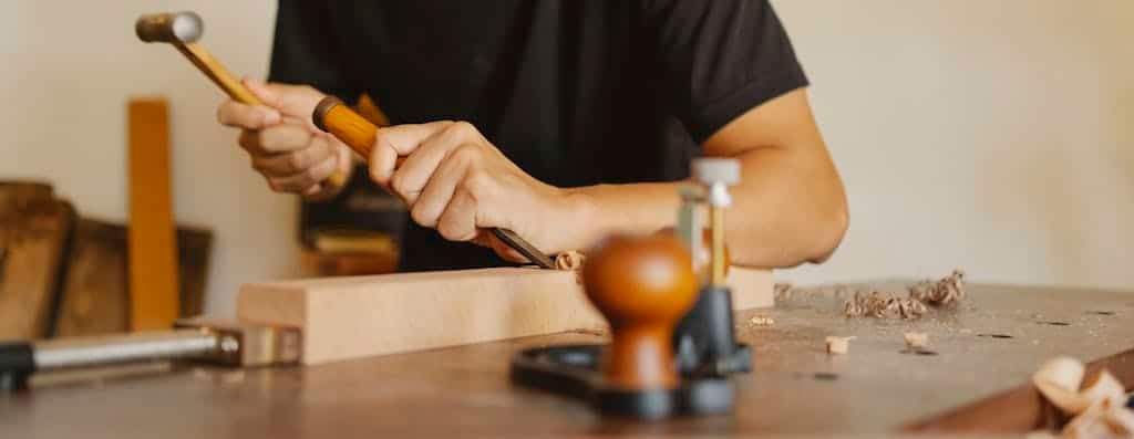 An artisan uses tools to craft detailed woodwork, showcasing precision and craftsmanship.