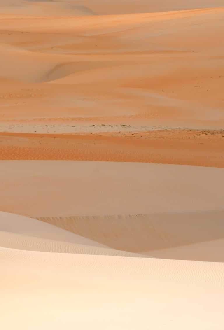 Beautiful layers of sand dunes under sunlight, showcasing the natural beauty of a vast desert.