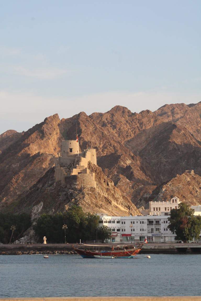 Beautiful view of Al Jalali Fort with mountains and boat in Muscat, Oman.