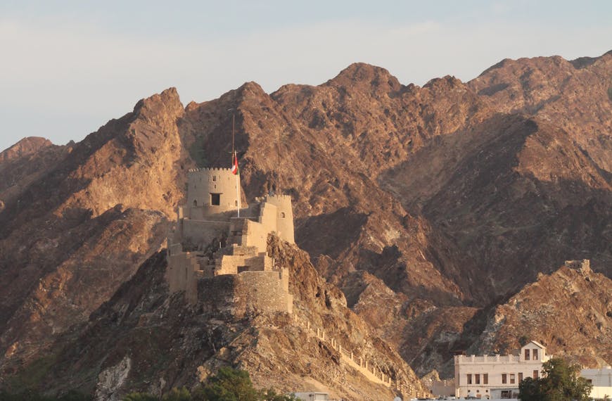 Beautiful view of Al Jalali Fort with mountains and boat in Muscat, Oman.