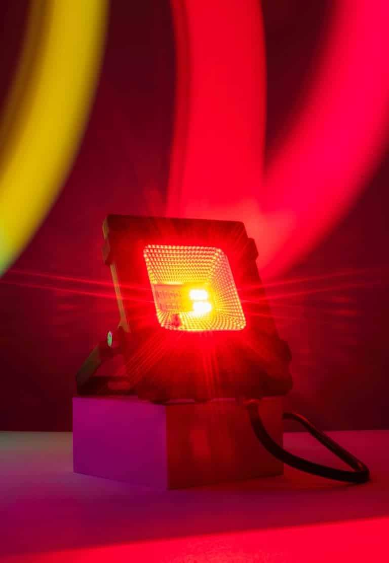 Dynamic and colorful LED spotlight casting vibrant red light with motion blur on a dark background.