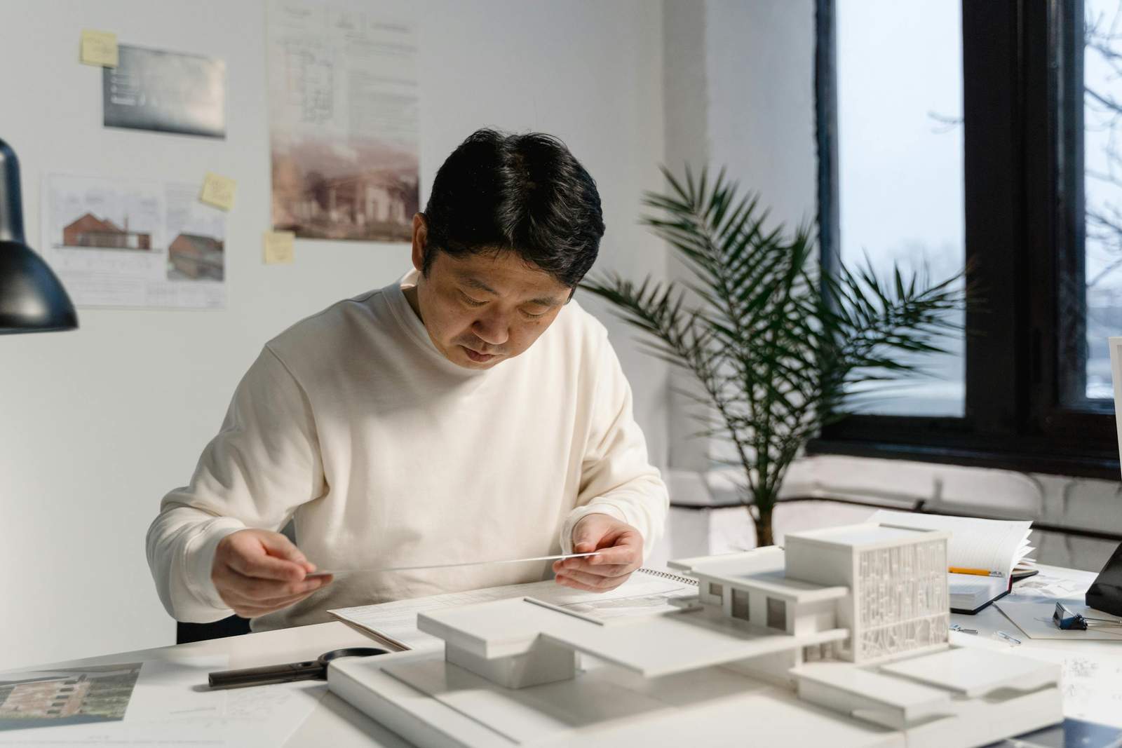 Architect engrossed in designing a modern building model at his workspace.