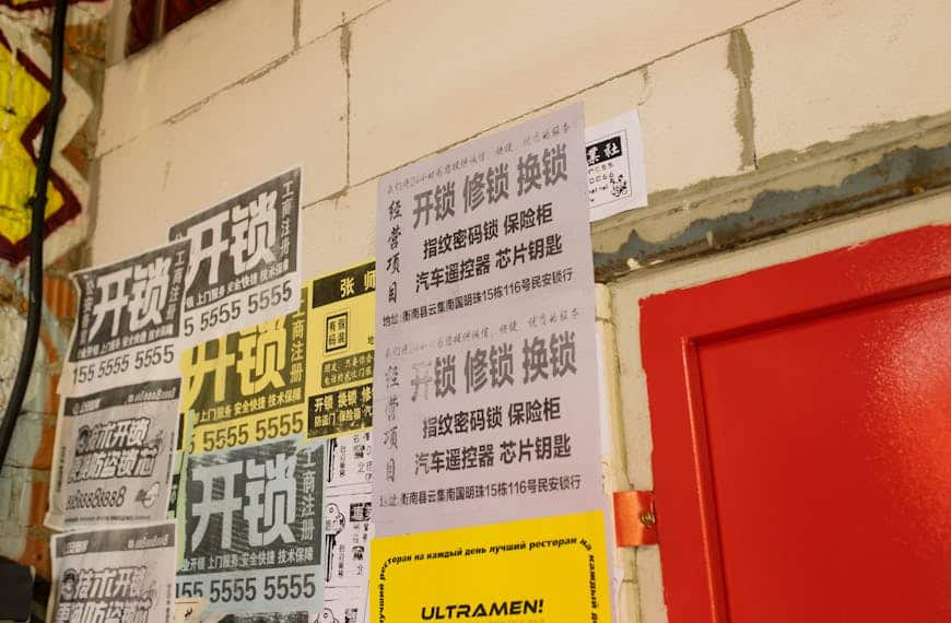 Asian language posters on a vibrant urban wall offering locksmith services.