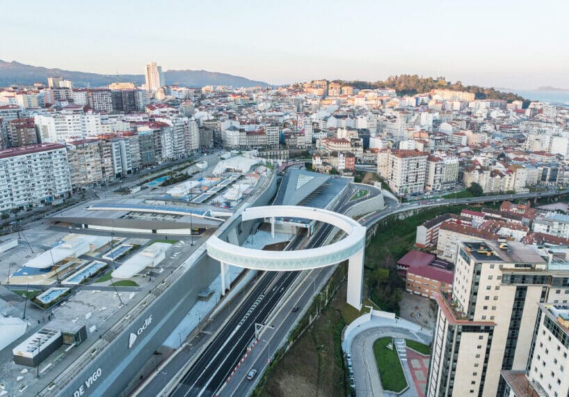 A modern circular pedestrian bridge spanning over a busy highway in an urban city