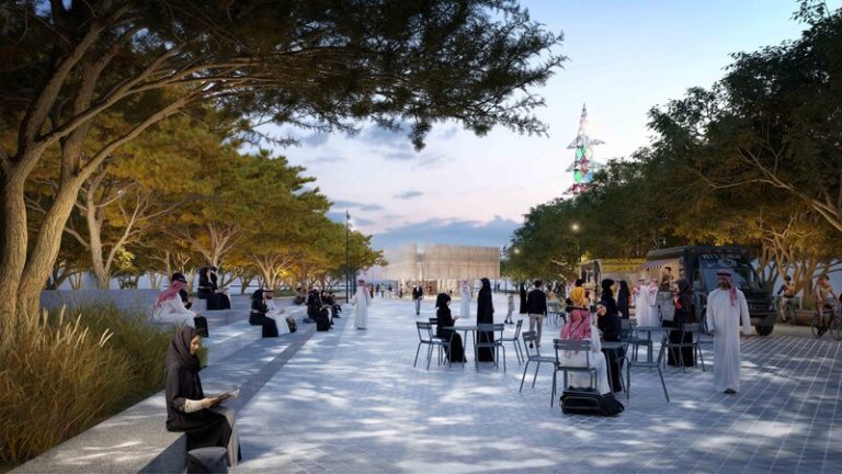 A spacious open area with people gathered around, surrounded by trees.