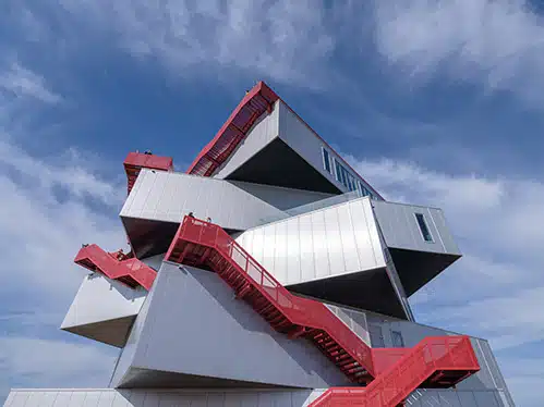 A stacked building with interlocking boxes and red exterior stairs
